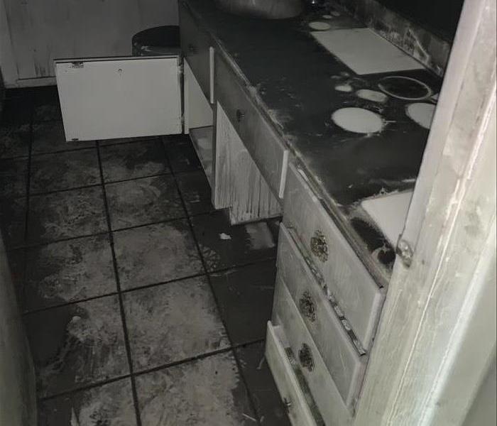 A heavily sooted vanity with clean white spots where items on the vanity had been during the fire