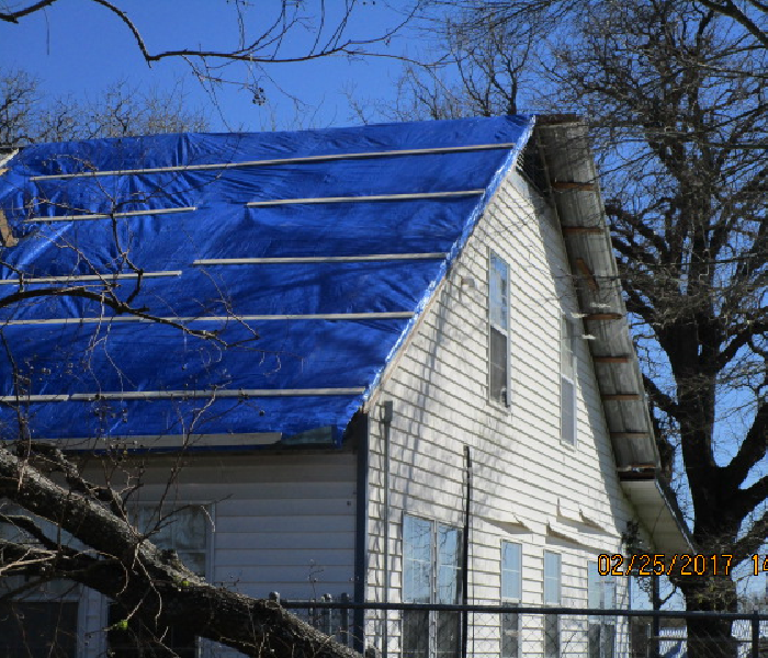 House roof extensively tarped up after a tornado
