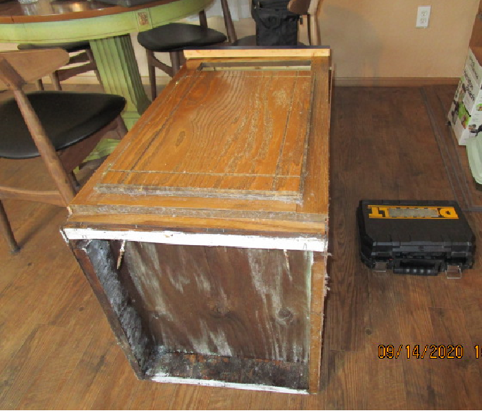 Small kitchen cabinet laying on its back showing mold on the toe kick area bottom