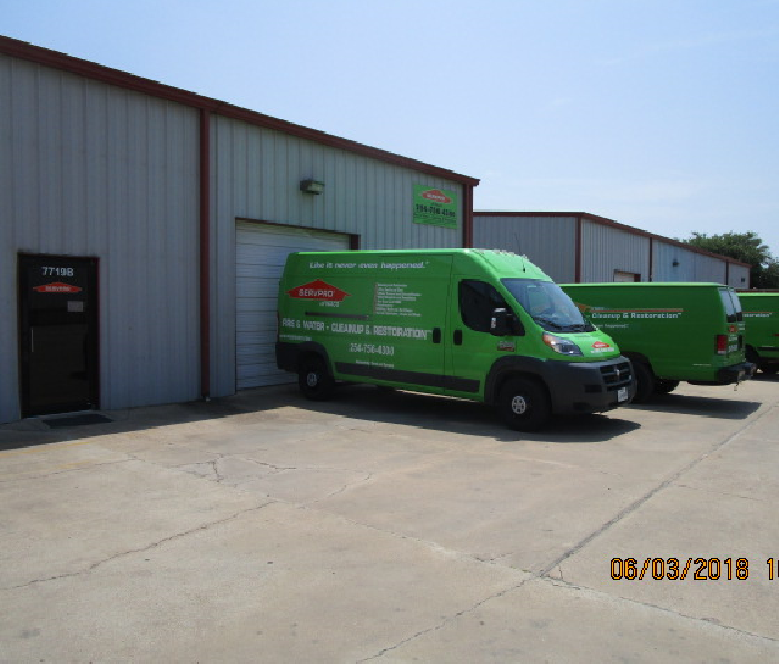 Picture of our warehouse front with our sign and three production vehicles