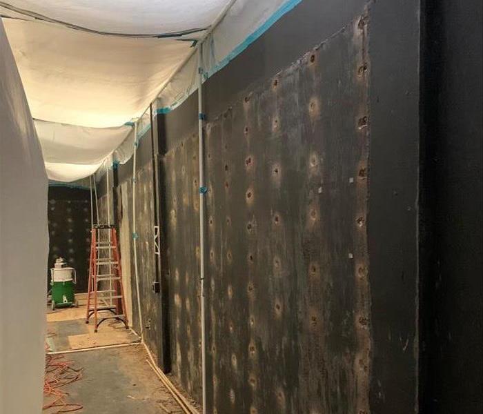 Black painted plywood wall with many holes drilled around the screws