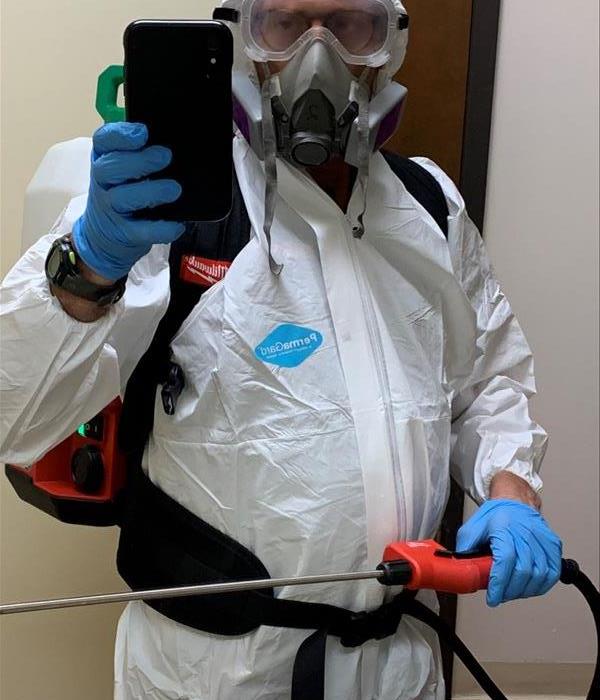 worker in tyvec suit with a backpack sprayer and ppe